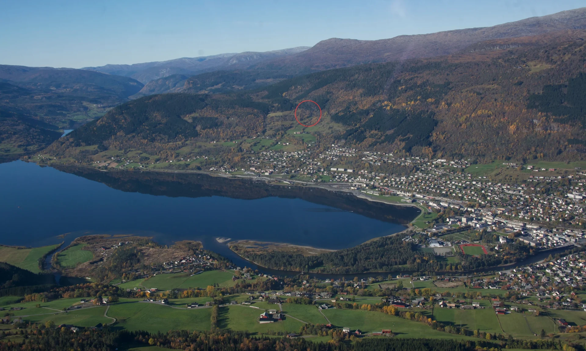Luftfoto over Voss med Vossavatnet, sentrum og fjella — raud ring markerer kor hytta ligg i lia